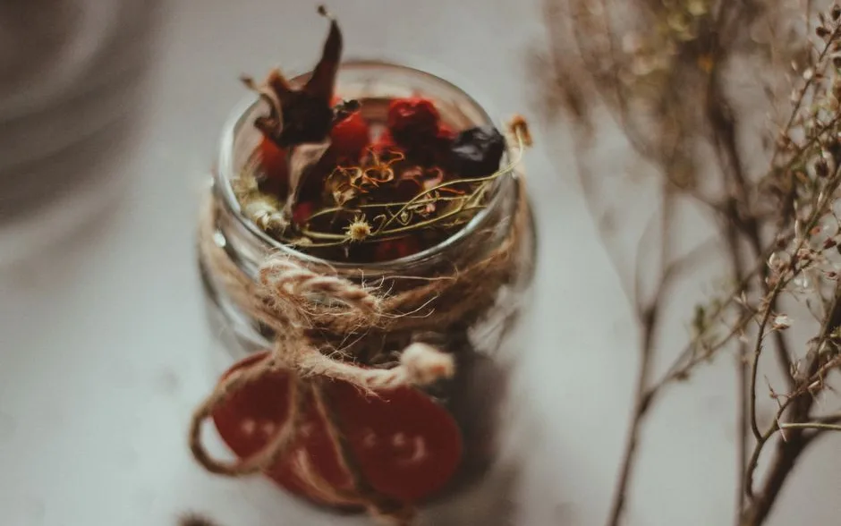 Bocal de tisane aux plantes séchées noué d’une ficelle, sur une table en bois